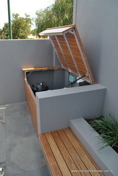 an open box sitting on top of a wooden bench next to a planter and window