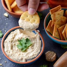 a person dipping some crackers into a bowl of dip