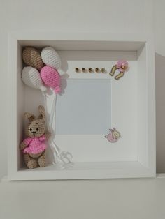 a teddy bear is sitting in front of a white frame with pink decorations on it