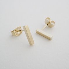 Petite, minimalist, straight drop bar stud earrings with a shiny finish. Length: 10 mm tall. Our materials make for an amazing, high quality, seamless, jewelry piece with longevity. Our earrings are plated with 18k gold, 18k rose gold, or rhodium and finished with a protective coating. A little secret we'll keep between us: it looks way more than it costs. Delicate Gold Jewelry, Gold Bar Earrings, Ear Climbers Earrings, Bar Stud Earrings, Bar Studs, Climber Earrings, Between Us, Hoop Earring Sets, Earrings Minimalist