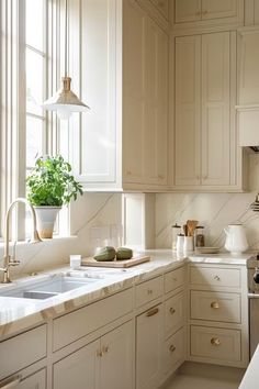 a kitchen filled with lots of white cabinets and counter top space next to a window