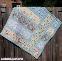 a baby quilt hanging on a wooden fence