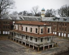 an old abandoned building sits in the middle of a parking lot next to some trees