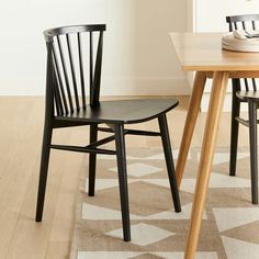 two black chairs sitting on top of a wooden floor next to a dining room table