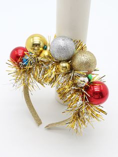 a candle is decorated with christmas ornaments and tinsel on the top, along with a gold ribbon