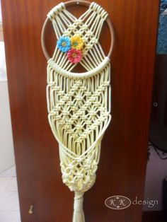 a white macrame hanging on a wall with flowers in the center and two circles around it