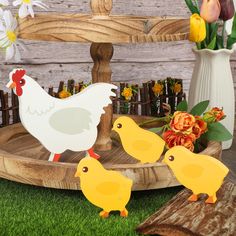 two chickens and one duck are standing in front of a wooden bench with flowers on it