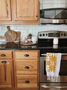 a kitchen with stainless steel appliances and wooden cabinets, including a dish towel hanging on the oven door