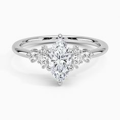 a white gold ring with three pear shaped diamonds on the band and an oval center stone