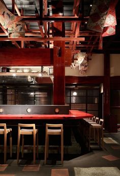 an empty bar with wooden chairs and red counter top in the middle of a room