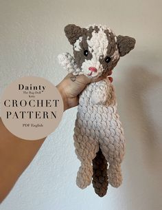 a hand holding a crochet stuffed animal in the shape of a cat with one eye open