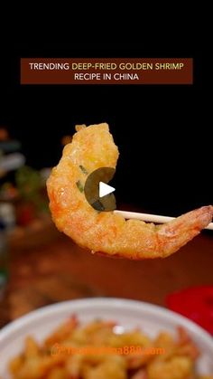 fried golden shrimp being held by chopsticks in front of a bowl of food