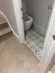 an open door leading to a bathroom with a toilet in the corner and wood flooring