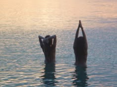 two people are standing in the water doing yoga poses with their hands behind their backs