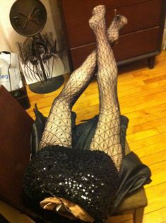 a woman in fishnet stockings laying on top of a chair with her legs up