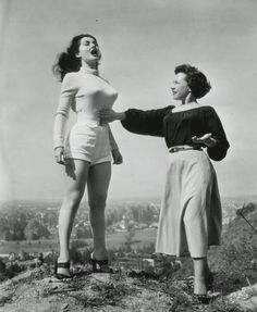 two women standing on top of a hill near each other