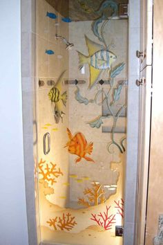 the shower door is decorated with fish and corals