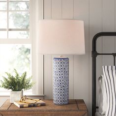 a blue and white vase sitting on top of a wooden table next to a lamp