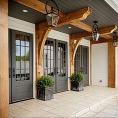 the front porch is decorated with potted plants and two large lanterns on each side