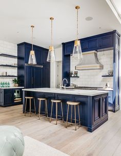 a large kitchen with blue cabinets and white counter tops is pictured in this image, the center island has gold bar stools