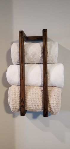 a stack of white towels sitting on top of a wooden rack next to a wall