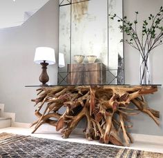 a table made out of driftwood in front of a mirror and lamp on the floor