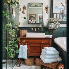 a bathroom with green walls and white towels on the sink, toilet, mirror and bathtub