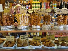 a woman standing behind a counter filled with food