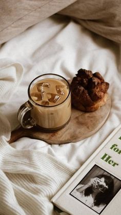 a cup of coffee next to a doughnut on a wooden plate with a book