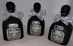 three black bottles with white and silver designs on them, one has a bow around the neck