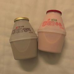 two yogurt cups sitting next to each other on a white tablecloth covered surface