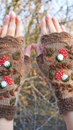 two hands wearing knitted mitts with flowers on them