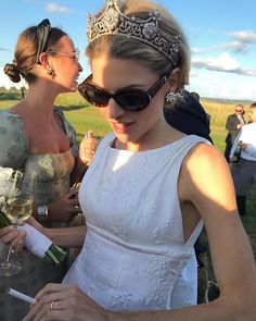 two beautiful women standing next to each other in front of a field with grass and flowers