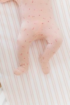 a pink baby's foot laying on top of a white and pink striped sheet