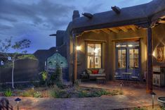 an adobe style house lit up at night with lights on the front door and patio