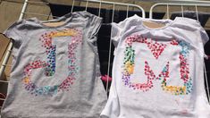 two t - shirts with the letters m and l are hung on a clothes rack