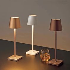 three lamps and a glass on a table