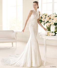 a woman in a white wedding dress standing next to a table with flowers on it