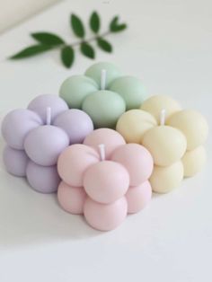 four small candles in pastel colors on a white surface