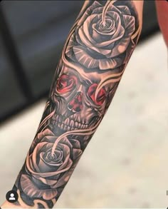 a man's arm with a skull and roses tattoo design on the left forearm