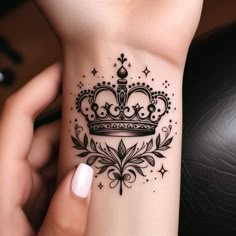 a woman's wrist tattoo with a crown and stars on the top of it