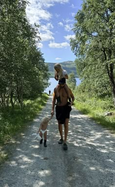 a woman walking down a dirt road with a dog on her back and trees in the background