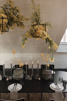 a dining room table with flowers and candles hanging from it's centerpieces