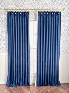 a blue curtain hanging on the side of a window in front of a white wall