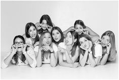 a group of young women posing for a photo in front of a white wall with their mouths open