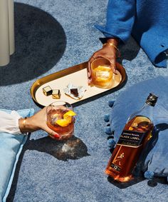 two people holding drinks and serving them on a tray with ice cubes in it