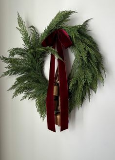 a green wreath with red ribbon hanging on the wall