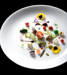 a white plate topped with assorted veggies on top of a black table