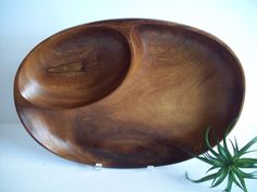 a wooden bowl sitting on top of a white table next to a green air plant