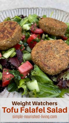 two patties on top of a salad with lettuce and tomatoes